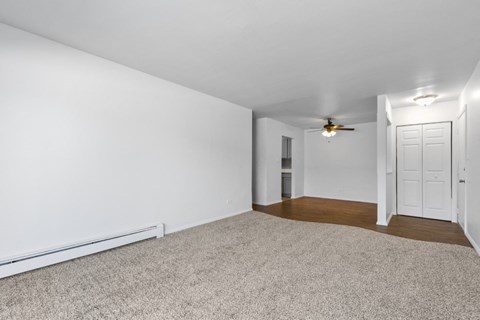 an empty living room with white walls and a ceiling fan