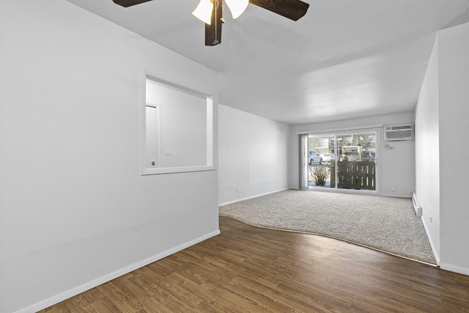 a living room with white walls and a window and a ceiling fan