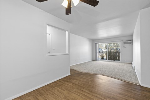 a living room with white walls and a window and a ceiling fan