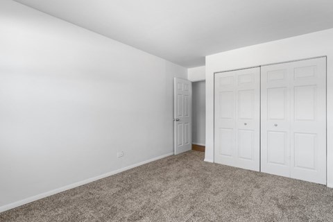 a bedroom with white walls and carpet and white doors