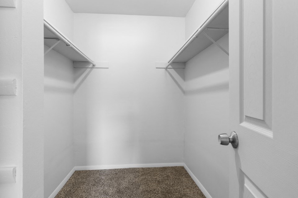 a walk in closet with two shelves and a door
