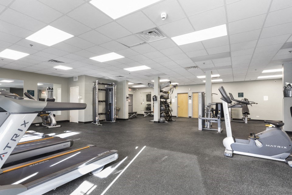 a gym with treadmills and other exercise equipment in a building with white ceilings