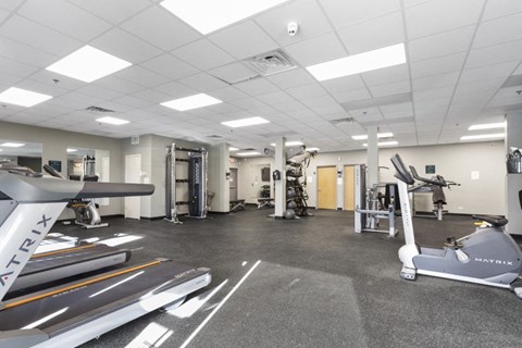 a gym with treadmills and other exercise equipment in a building with white ceilings