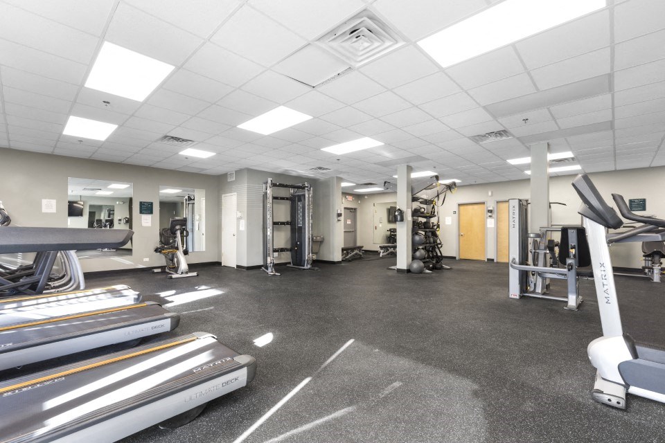 a gym with cardio equipment and weights on the floor