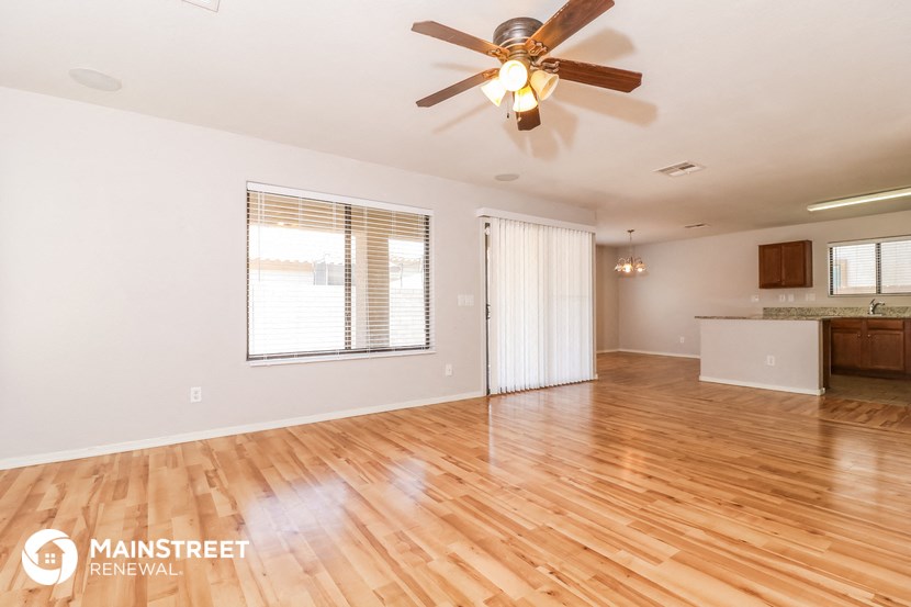 the living room and dining room with wood flooring and a ceiling fan