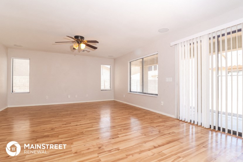 the living room with wood floors and a ceiling fan