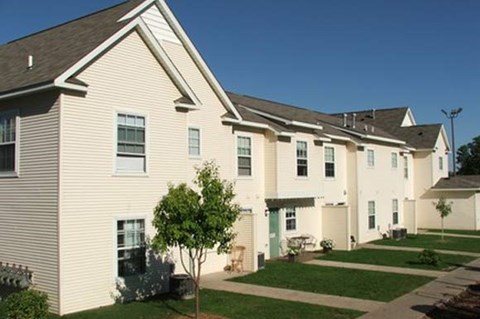 a row of houses with white siding and green grass
