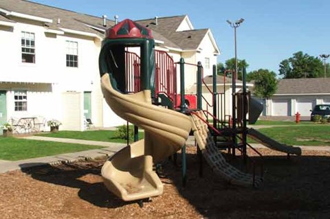 a playground with a slide in front of a house
