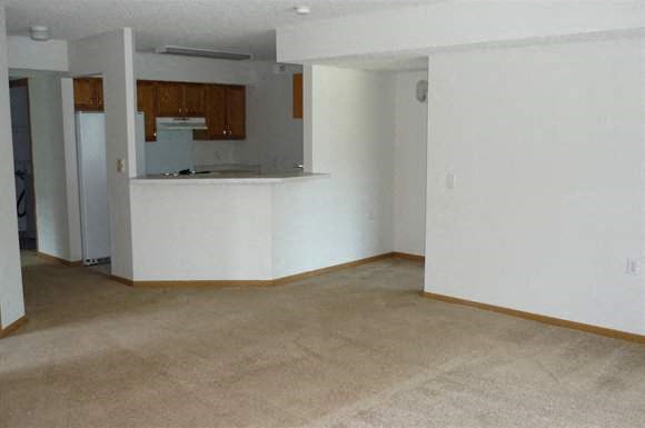 an empty living room with a kitchen in it
