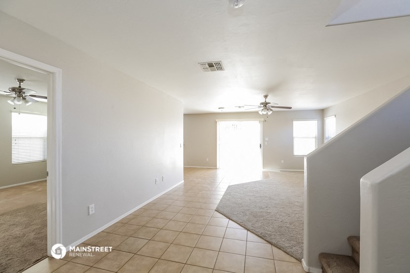 an empty living room with a ceiling fan and a carpet