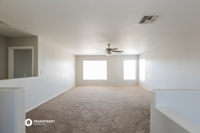 an empty living room with a ceiling fan and white walls