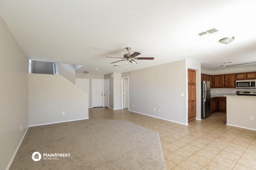 an empty living room and kitchen with a ceiling fan