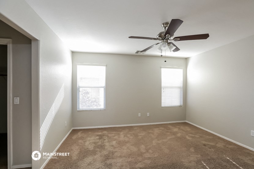 an empty room with a ceiling fan and a window