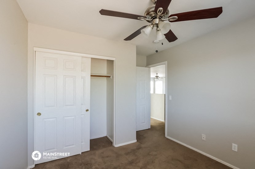 a bedroom with a ceiling fan and a closet
