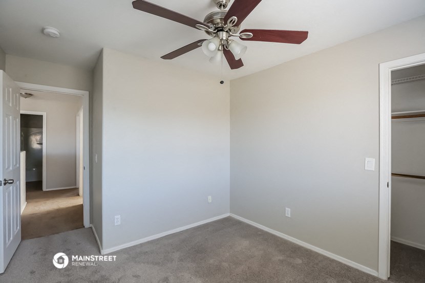 an empty room with a ceiling fan and a closet