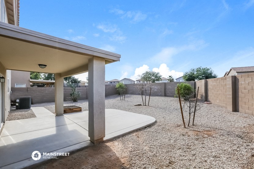 the backyard of a home with a patio and a fence