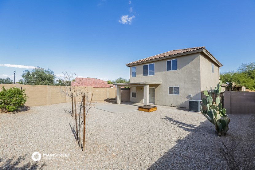 a white house with a gravel driveway and a cactus
