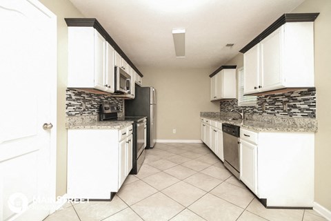 a kitchen with white cabinets and appliances and a tile floor