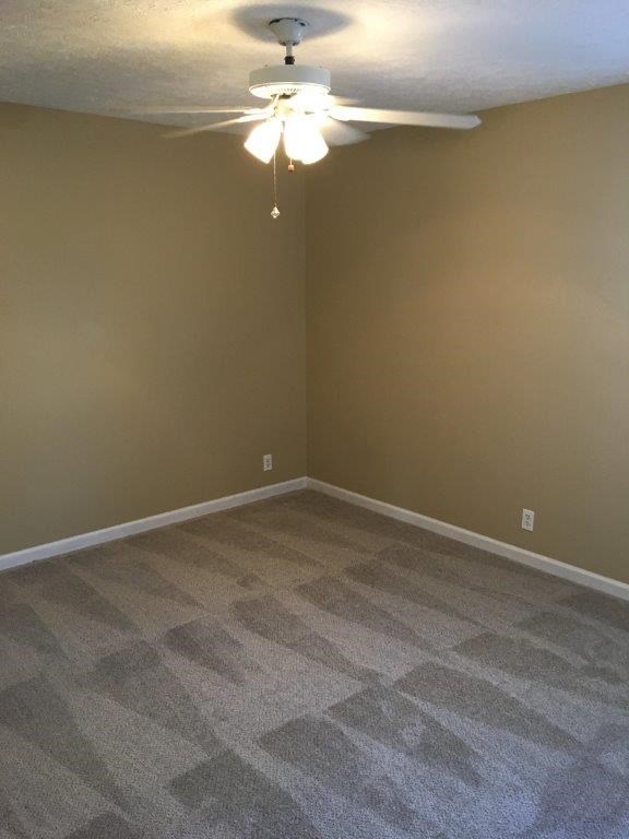 an empty living room with a ceiling fan and