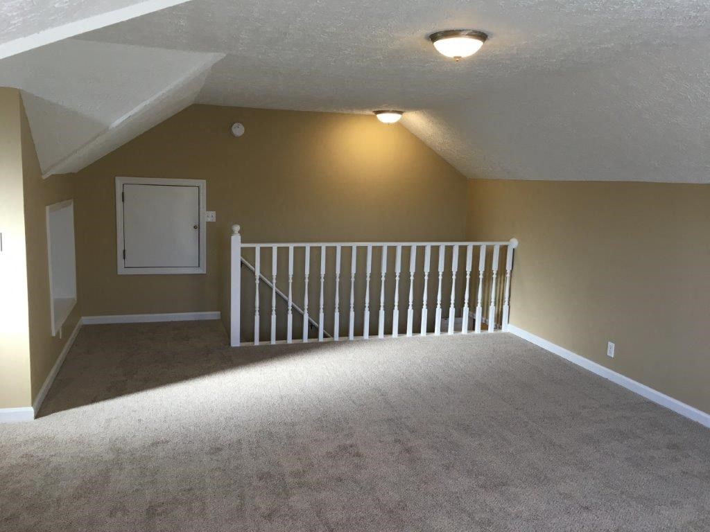 an empty loft with a white railing and a white door
