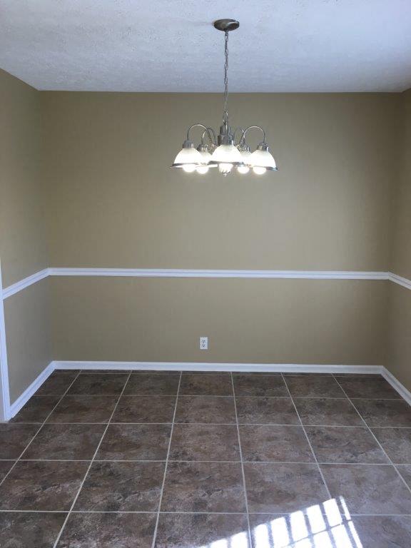 a empty room with a chandelier and tiled floor
