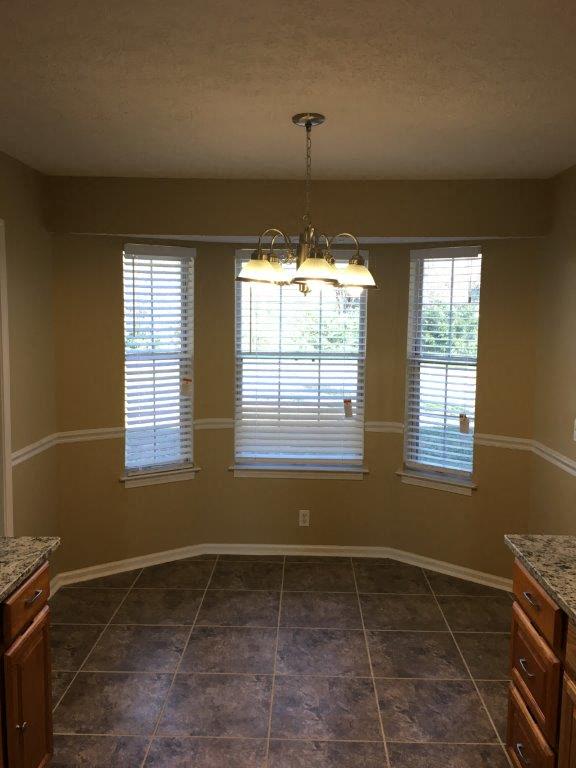 an empty dining room with three windows and a chandelier