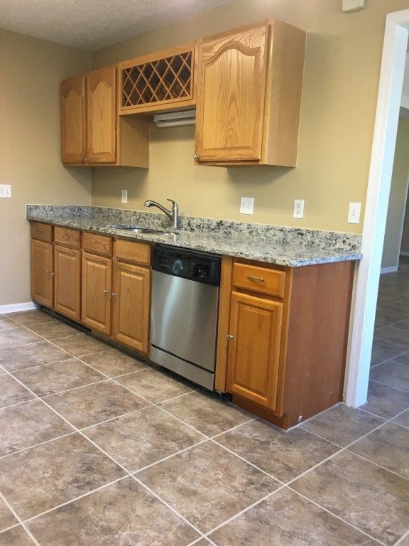 a kitchen with wooden cabinets and a stainless steel dishwasher