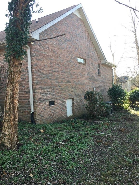 a brick house with a white door and a tree