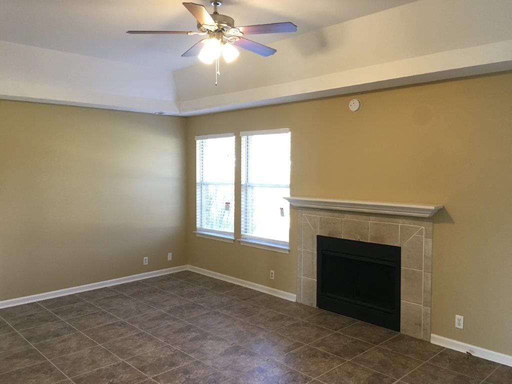 a living room with a fireplace and a ceiling fan