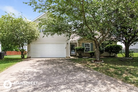 a house with a driveway and trees in front of it