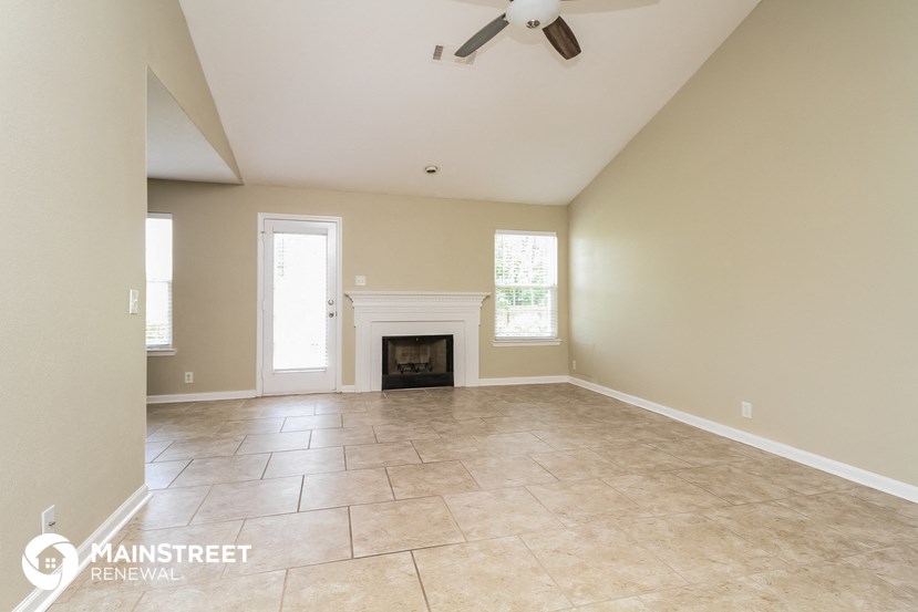 an empty living room with a fireplace and tile flooring