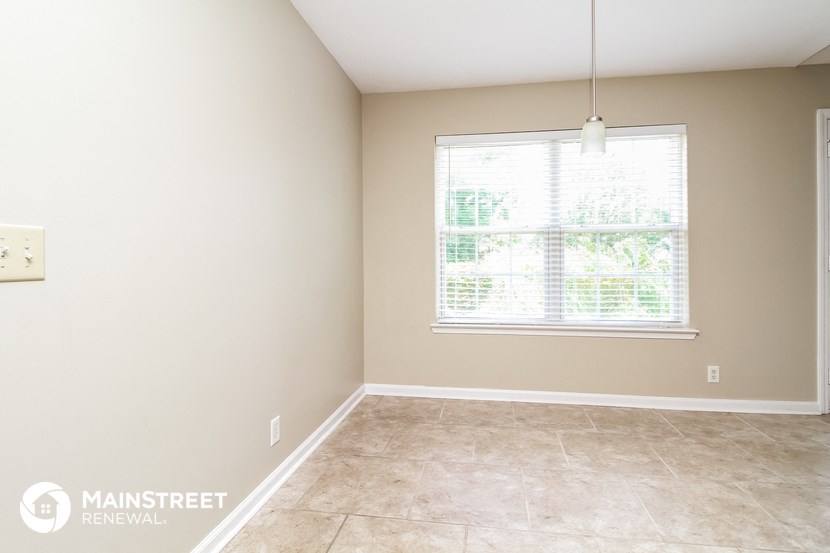 an empty room with a large window and tiled flooring