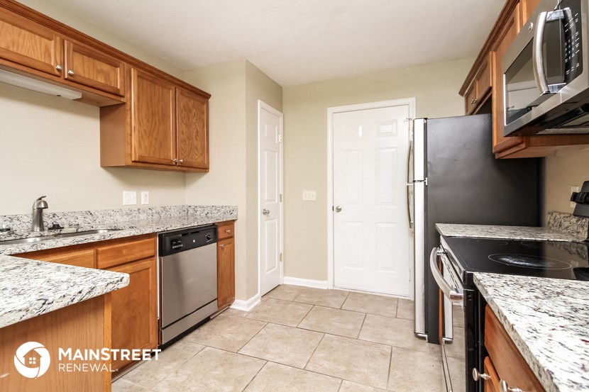 a kitchen with wooden cabinets and granite counter tops and a black refrigerator