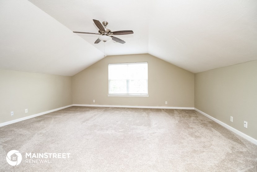 the master bedroom has a carpeted floor and a ceiling fan