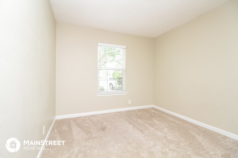 a spacious bedroom with carpet and a window