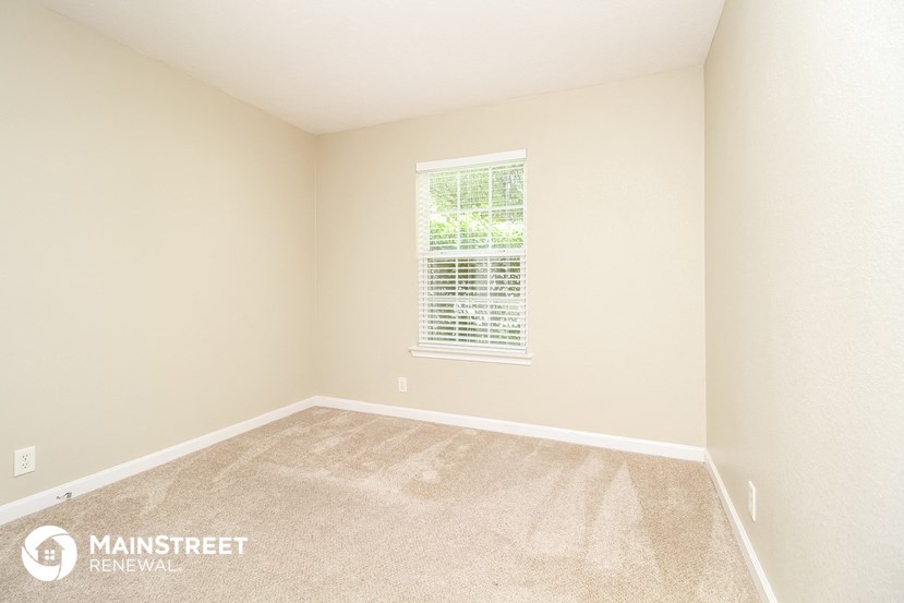 a bedroom with a large window and a carpeted floor