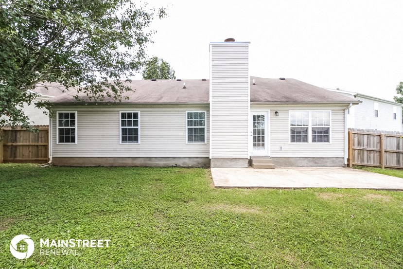 the back of a white house with a concrete porch and a yard