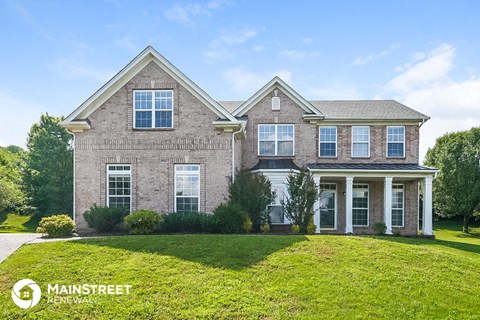 a large brick house with a green lawn in front of it