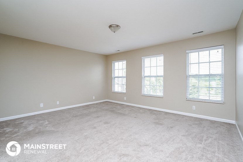 the spacious living room with carpet and three windows