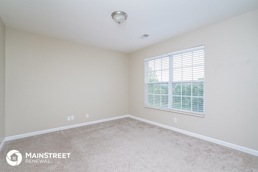 the master bedroom has a carpeted floor and a large window