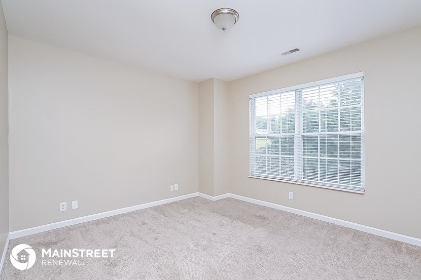the master bedroom has a carpeted floor and a large window