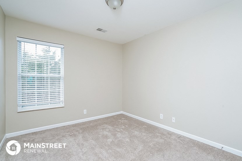 a bedroom with a large window and a carpeted floor