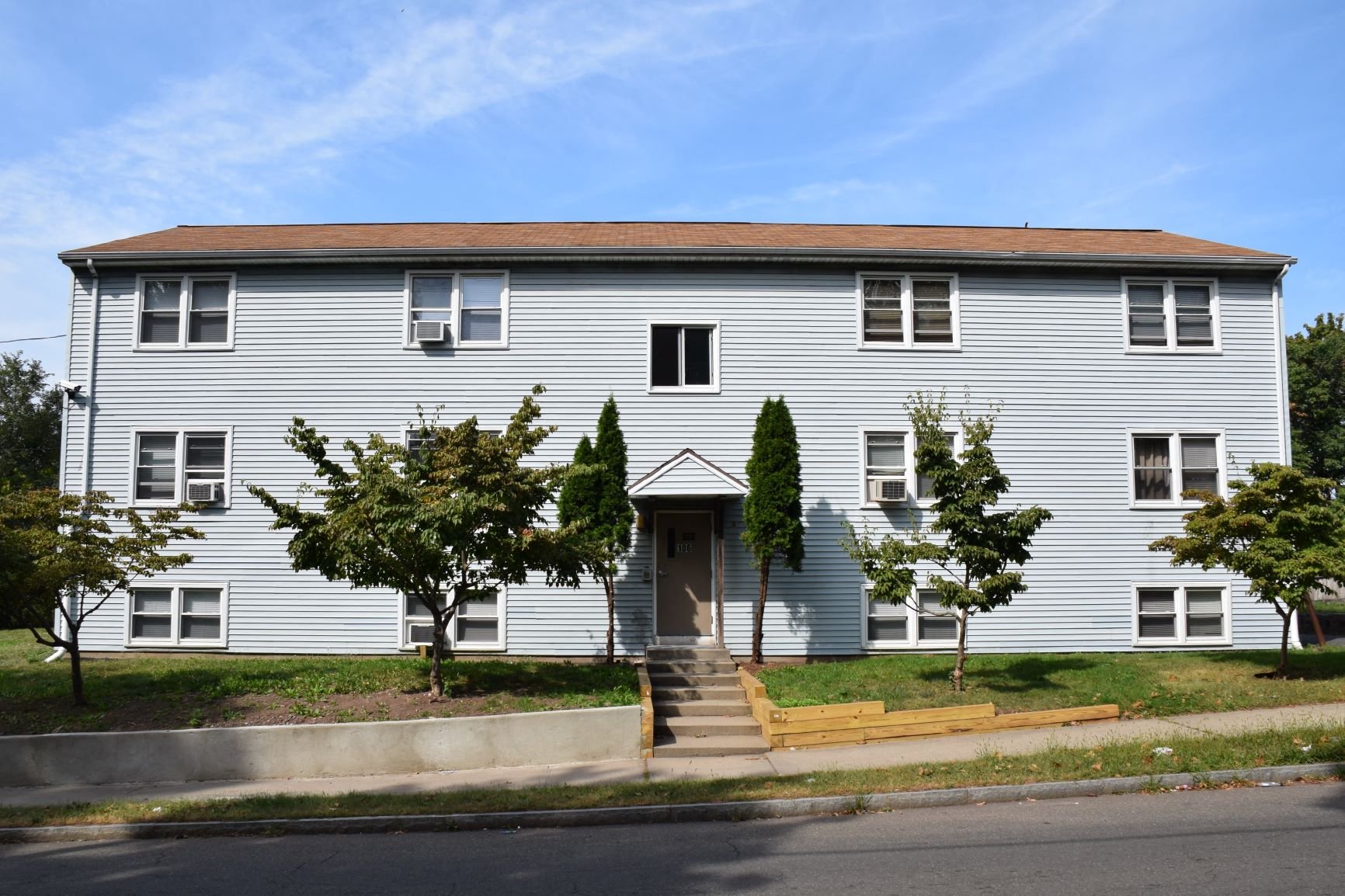 A grey house with a brown roof and a front door.