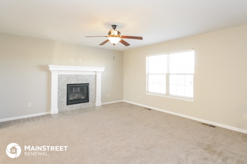 the living room with fireplace and ceiling fan
