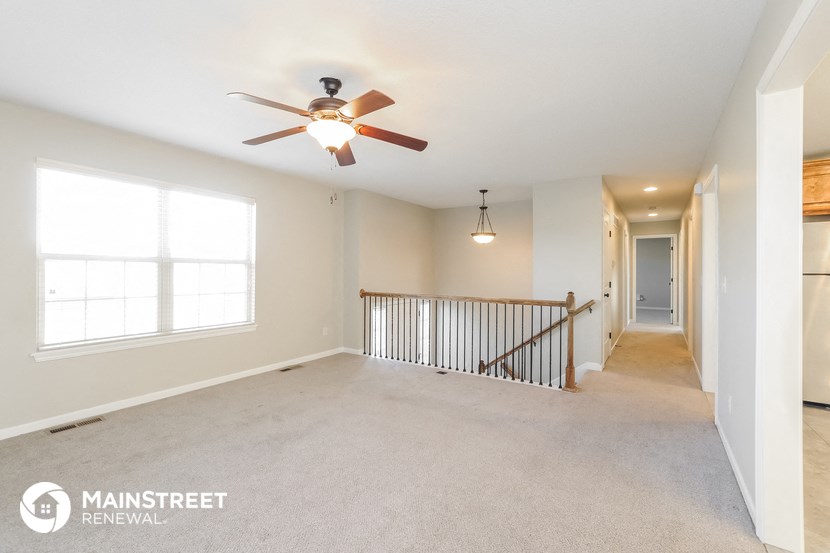 an empty living room with a ceiling fan and a large window
