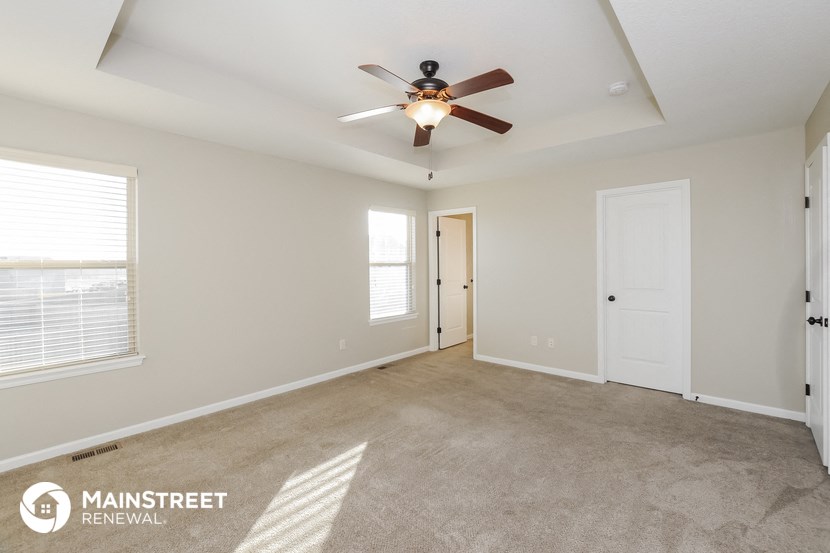 the spacious living room with ceiling fan and carpeting