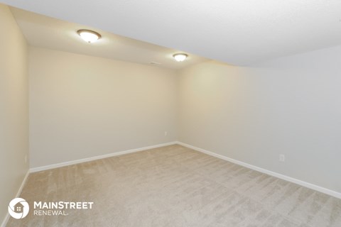 the spacious living room of this manufactured home has white walls and beige carpet