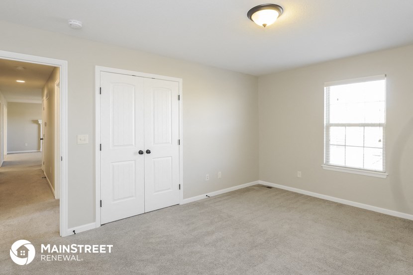 a bedroom with two doors and a carpeted floor and a door to a hallway