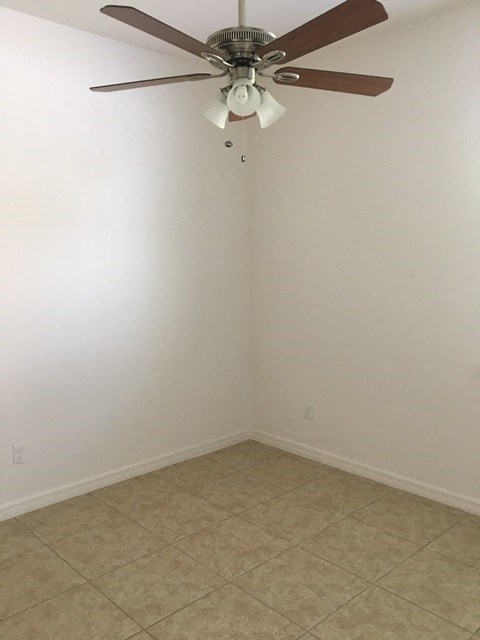 an empty room with a ceiling fan and a tiled floor