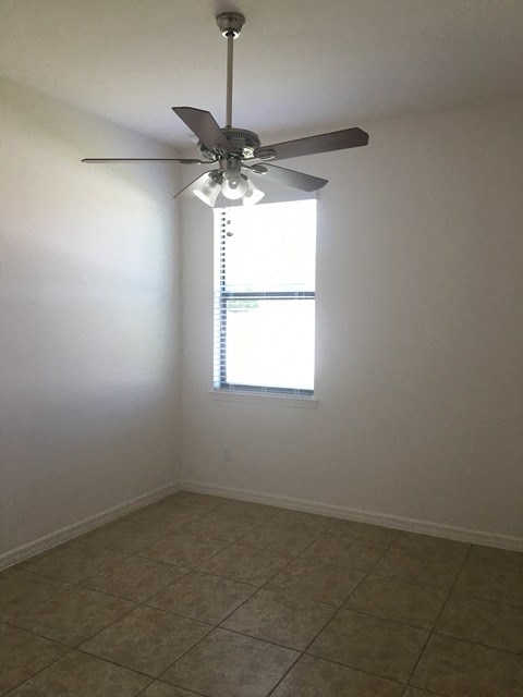 an empty room with a ceiling fan and a window